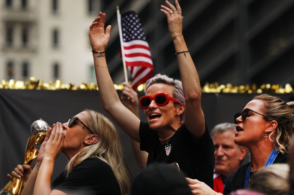Ali Krieger, Megan Rapinoe, and Ashlyn Harris celebrate while riding on a float during the US Women's National Soccer Team Victory Parade through the Canyon of Heroes in New York City, on Wednesday. The team defeated the Netherlands 2-0 on Sunday in France to win the 2019 Womens World Cup. — AFP