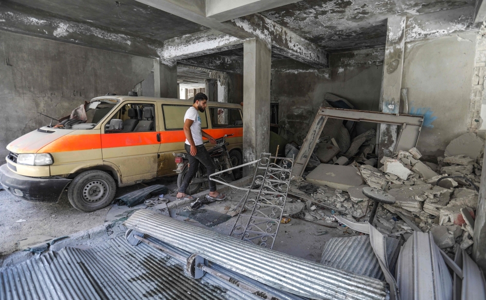 A man walks past a damaged mini-van that was used as a make-shift ambulance amidst debris in the garage of a hospital damaged after a reported air strike in Jisr Al-Shughur in the northeastern Syrian Idlib province on Wednesday. — AFP