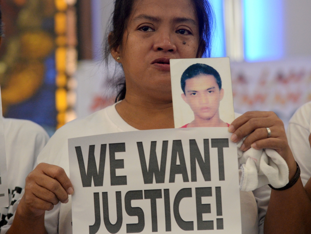 A woman displays a picture of her son, a drug war victim, and a placard during a protest against the war on drugs by President Rodrigo Duterte in Quezon city, Metro Manila in Philippines, in this Aug. 28, 2018 file photo. — Reuters