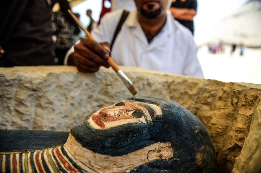 A man brushes off dust from a sarcophagus, part of a new discovery carried out almost 300 meters south of King Amenemhat II’s pyramid at Dahshur necropolis, exposed near the Bent Pyramid, about 40km (25 miles) south of the Egyptian capital Cairo, during an inaugural ceremony of the pyramid and its satellites, on Saturday. — AFP