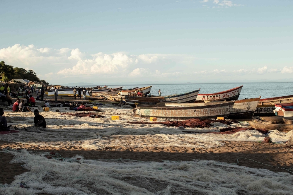 Malawian fishermen fix their fishing nets as fishing boats are seen on the shore of the Lake Malawi at the Senga village on May 19, 2019 in Senga, Malawi.  -AFP photo