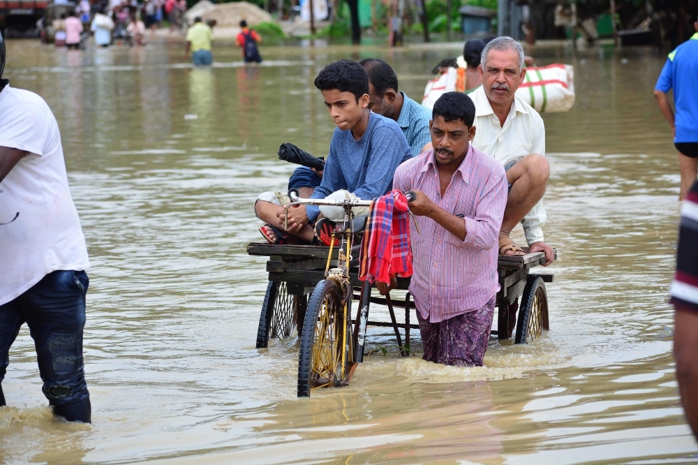 An Indian rickshaw driver transports commuters on a flooded street after a heavy downpour at Baldakhal village in Agartala, the capital of northeastern state of Tripura, on Sunday. -AFP photo