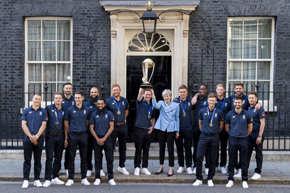 (L-R) England's Tom Curran, England's Jos Buttler, England's James Vince, England's Chris Woakes, England's Moeen Ali, England's Adil Rashid, England's Jonny Bairstow, England's captain Eoin Morgan, Britain's Prime Minister Theresa May, England's Jason Roy, England's Jofra Archer, England's Joe Root, England's Ben Stokes, England's Mark Wood, England's Liam Plunkett and England's Liam Dawson pose for a photograph outside 10 Downing Street with the World Cup trophy as England players arrive for a reception in London on Monday, a day after they won the 2019 Cricket World Cup after beating New Zealand the final at Lord's. — AFP