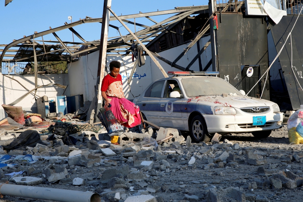 A migrant picks up clothes from among rubble at a detention center for mainly African migrants that was hit by an air strike in the Tajoura suburb of the Libyan capital of Tripoli in this July 3, 2019 file photo. — Reuters