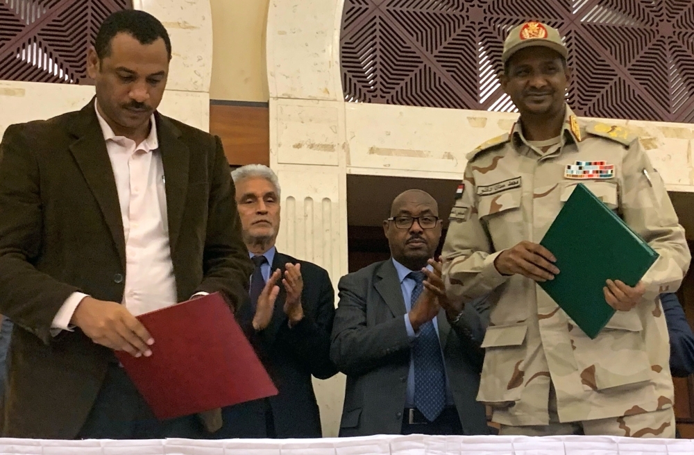 Sudanese deputy chief of the ruling military council Mohamed Hamdan Dagalo (R) and protest movement Alliance for Freedom and Changes leader Ahmad Al-Rabiah stand after inking an agreement before African Union and Ethiopian mediators in Khartoum early on Wednesdau. -AFP photo