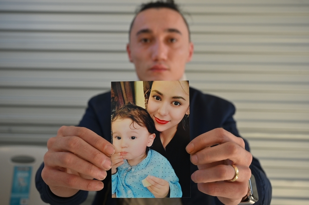 Sadam Abdusalam holds up a photo of his Uighur wife Nadila Wumaier and their baby son Lutifeier at a restaurant in Sydney's western suburbs on Wednesday. -AFP photo 