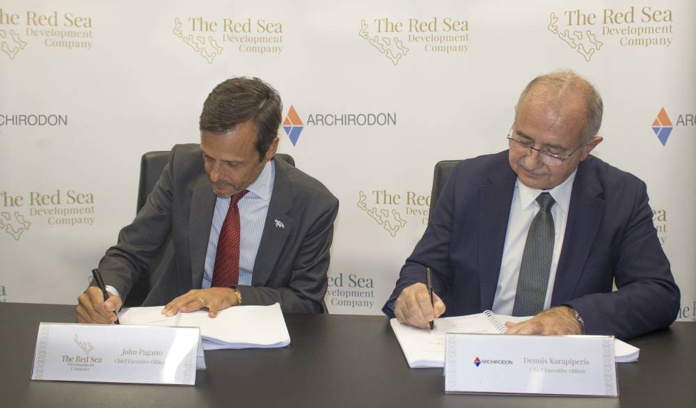 John Pagano, CEO of The Red Sea Development Company (left), and Dennis Karapiperis, CEO of Archirodon, sign the contract