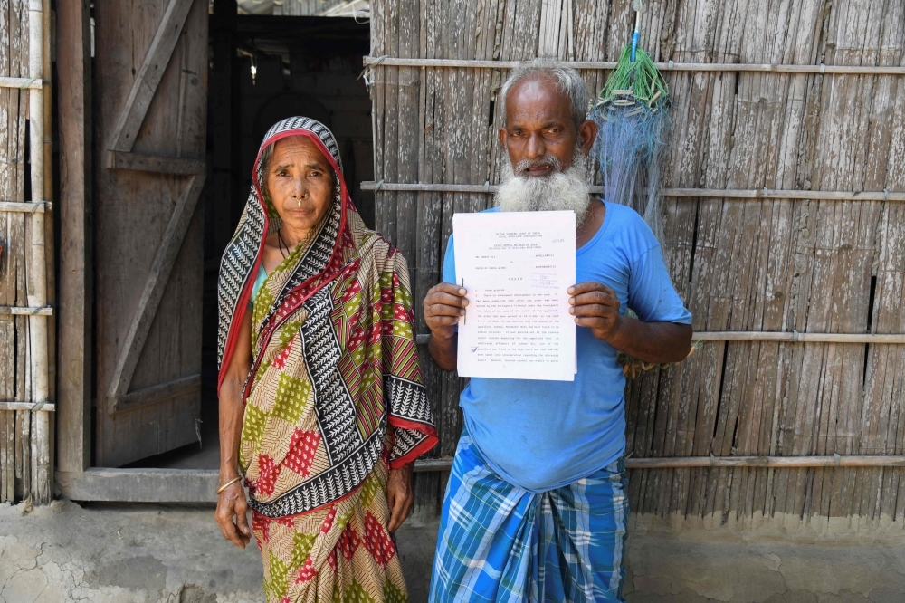 Mohammed Rehat Ali (R), 71, one of many to fall foul of a citizenship process in the north-eastern Indian state of Assam, holds a Supreme Court of India's order declaring him an Indian citizen as he stands with his wife Joiful Begum at his home at Khopnikuchi village in Assam's Kamrup district in this July 1, 2019 file photo. — AFP