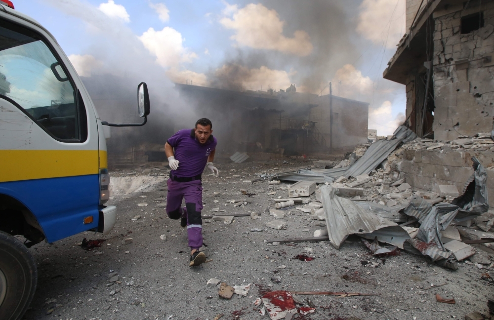 A Syrian rescuer from the Violet NGO runs during airstrikes by Syrian regime forces in Maar Shurin on the outskirts of Maaret Al-Numan in northwest Syria in this July 16, 2019 file photo. — AFP