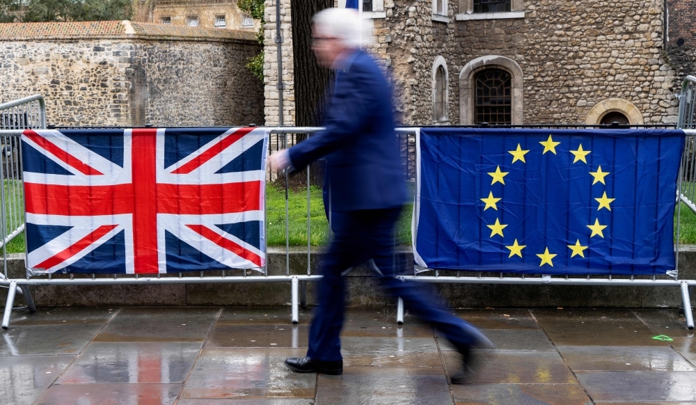 A pedestrian walks past the Union, left, and EU flags of anti-Brexit activists near the Houses of Parliament in London in this March 18, 2019 file photo. — AFP