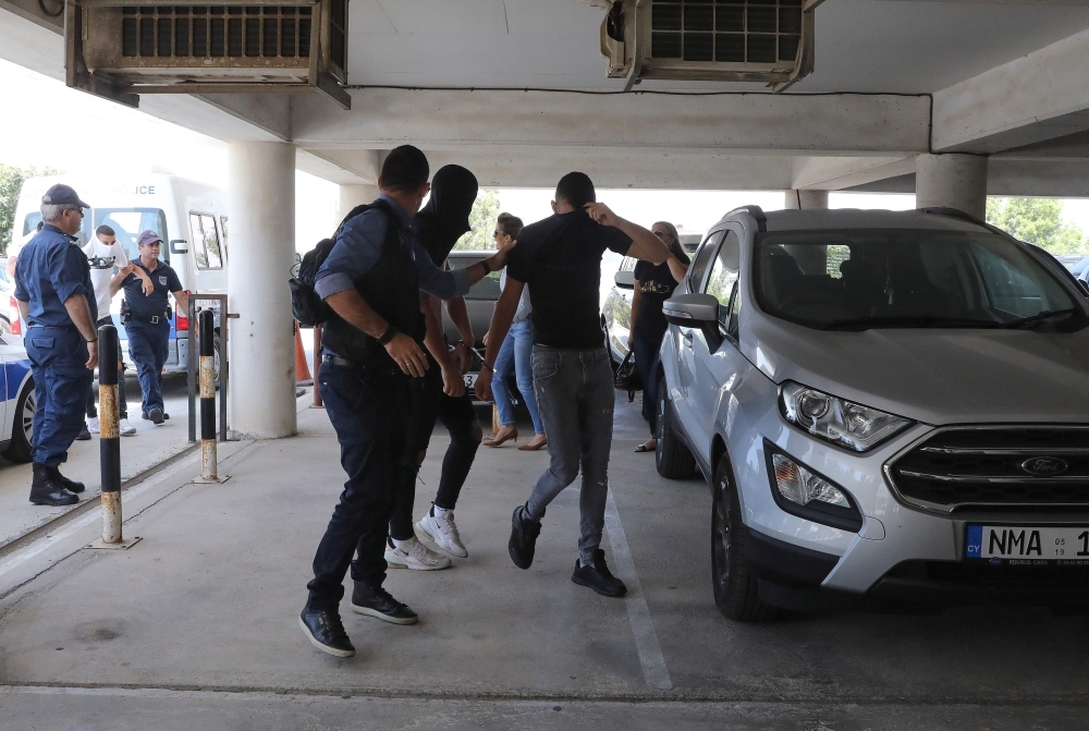 Twelve Israeli tourists, suspected of raping a 19-year-old British girl in Ayia Napa, arrive to the court premises with their faces covered in the eastern Cypriot resort of Paralimni on Thursday. — AFP
