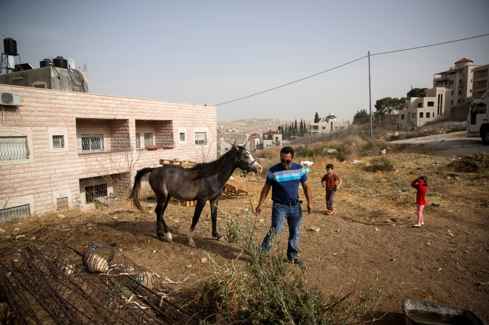Ismail Obeideh walks with his horse near his home in the Palestinian village of Sur Baher, which sits on either side of the barrier in East Jerusalem and the Israeli-occupied West Bank, on Wednesday. — Reuters
