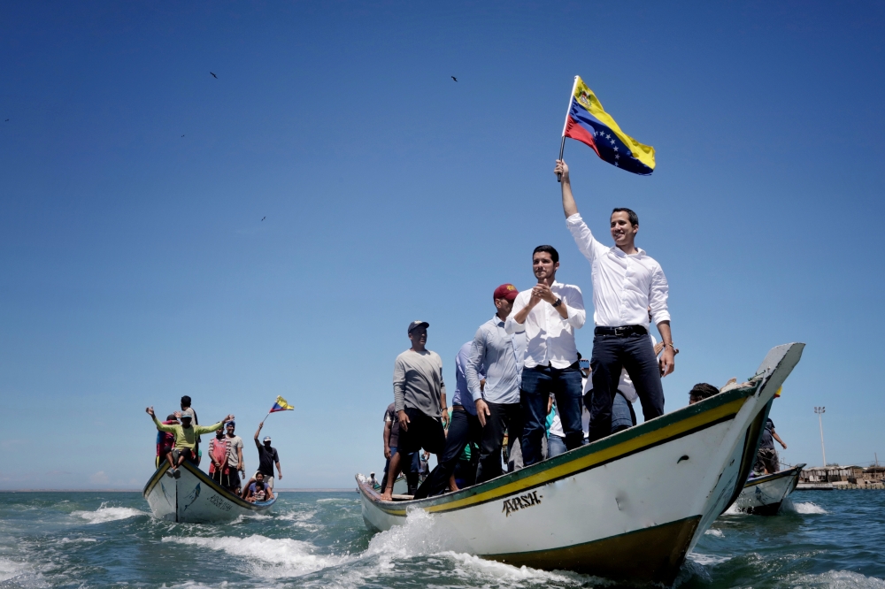 Venezuelan opposition leader Juan Guaido waves a national flag as he arrives in a boat for a meeting with supporters near Porlamar, Isla de Margarita, Venezuela, on Thursday. — Reuters