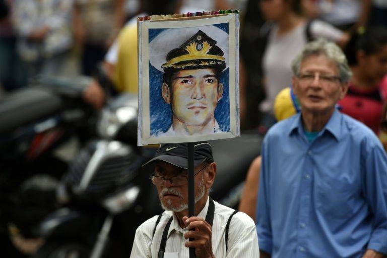 A man in Caracas holds up a portrait of Venezuelan retired naval officer Rafael Acosta, who was allegedly tortured before his death. –AFP photo