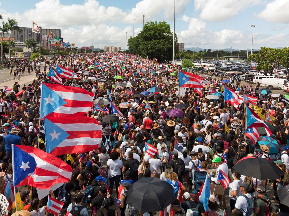 People gather along a main highway during a protest calling for the resignation of Governor Ricardo Rossello in San Juan, Puerto Rico on Monday. -Reuters