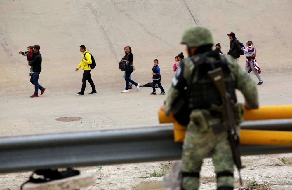 A member of the Mexican National Guard observes a group of migrants that crossed illegally into El Paso, Texas, U.S., as seen from Ciudad Juarez, Mexico on Monday. -Reuters photo