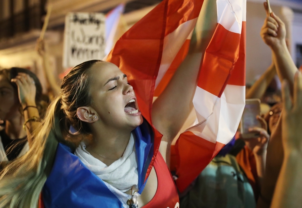  People react after hearing, while demonstrating near the governor's mansion, reports that Gov. Ricardo Rossello will step down, on Tuesday in Old San Juan, Puerto Rico. -Courtesy photo
