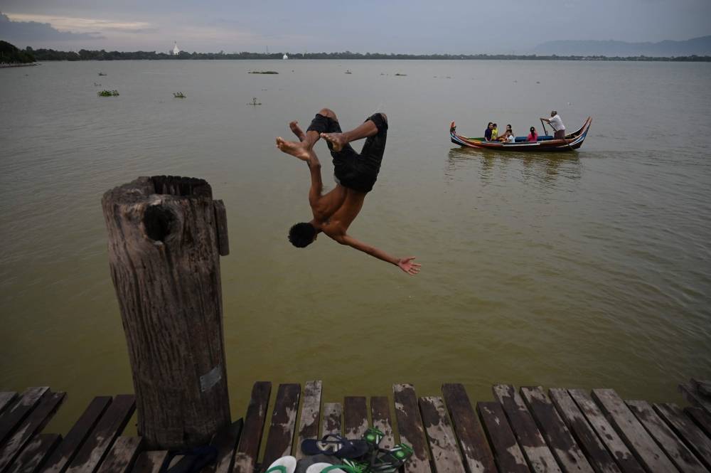 This photo taken on Sunday shows a man jumping to Taung Tha Man Lake from U Bein bridge in Mandalay, northern Myanmar. — AFP