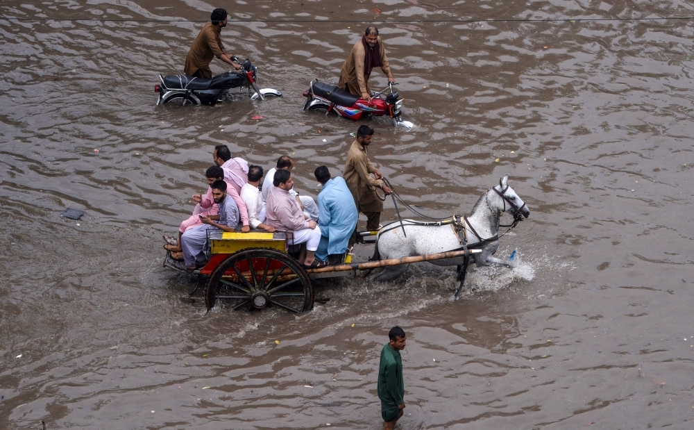 Pakistani residents ride on a horse cart through a flooded street during heavy monsoon rains in Lahore on Thursday. — AFP