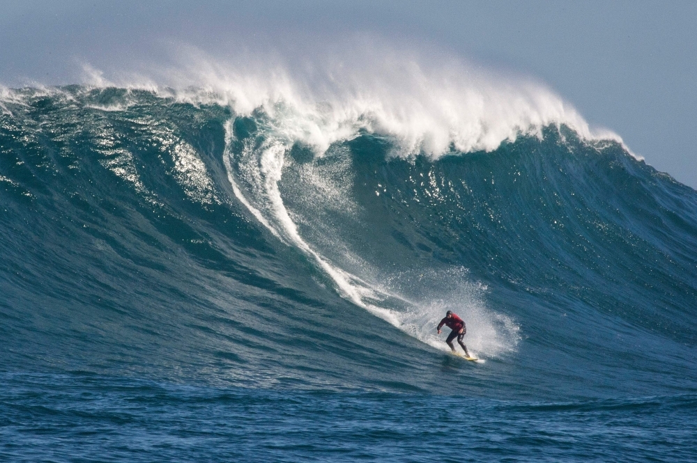 A surfer catches a wave at Dungeons, a famous surfing spot, close to Hout Bay, in Cape Town, South Africa, on Friday.  This spot, which produces some of South Africa's biggest waves, needs a variety of conditions like wind, swell size, wave period and direction, that often follows storms, to produce huge waves on an offshore reef, which attracts and challenges the surfers. — AFP