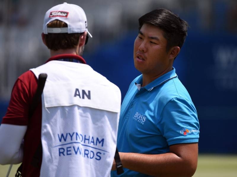 Byeong Hun An (R) talks to his caddie on the eighteenth green during the first round of the Wyndham Championship golf tournament at Sedgefield Country Club, on Thursday. — Reuters
