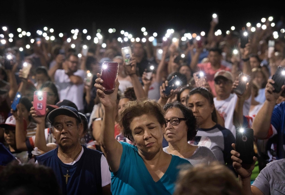 People hold up their phones during a prayer and candle vigil organized by the city, after a shooting left 20 people dead at the Cielo Vista Mall Wal-Mart in El Paso, Texas, on Sunday. — AFP