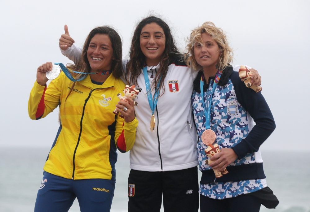 Peru's Daniella Rosas celebrates with Ecuador's Dominic Baruna and Argentina's Ornella Pellizari on the podium after winning gold, silver and bronze respectively in the women's open surfing final at Punta Rocas Complex, Lima, Peru, on Sunday. — Reuters
