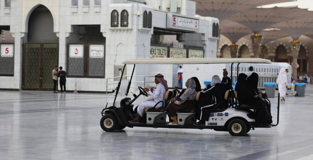 Women pilgrims take a ride in a golf cart. — SPA