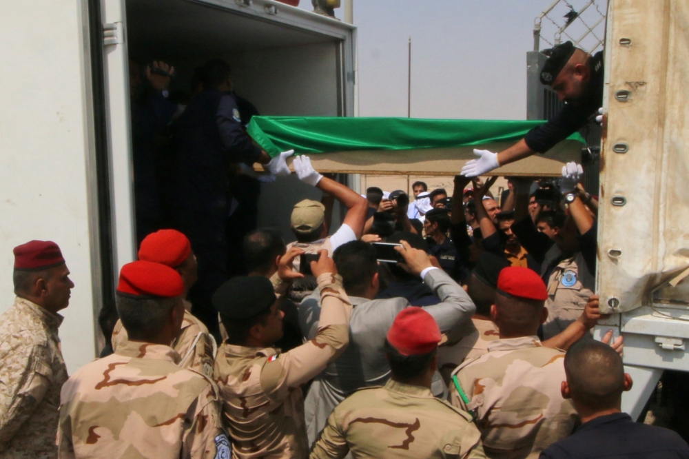 Iraqi soldiers hand over the remains of dozens of Kuwaiti citizens missing since the first Gulf war to Kuwaiti policemen in Basra, Iraq, on Thursday. — Reuters