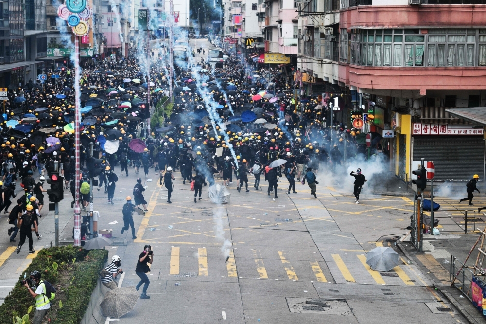 Pro-Democracy protesters throw back tear gas fired by the police during a demonstration against the controversial extradition bill in Sham Shui Po district in Hong Kong on Sunday. — AFP