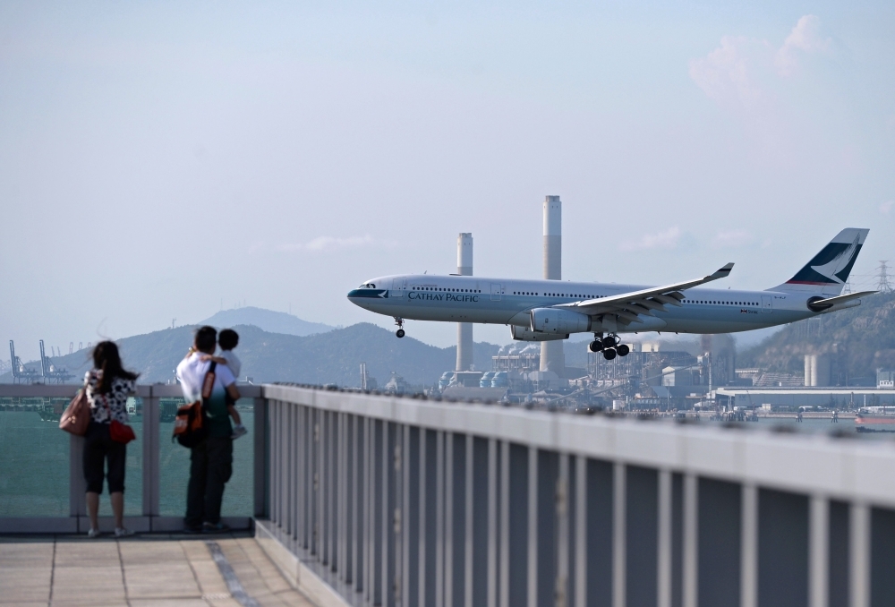 This file photo taken on August 10, 2014 shows people watching a Cathay Pacific passenger plane land at Hong Kong's international airport. -Courtesy photo