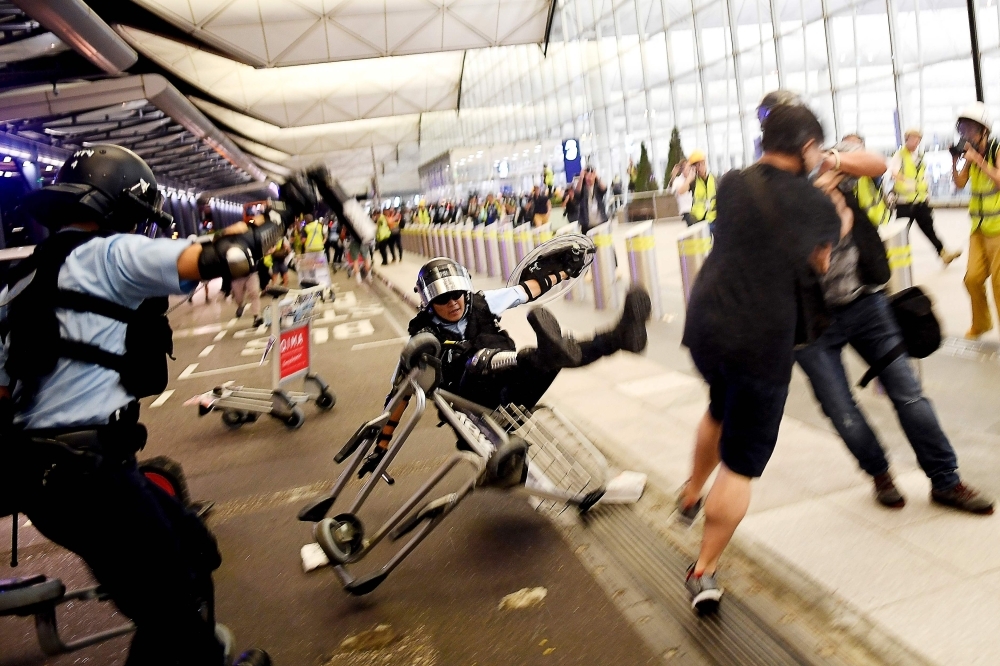 A Hong Kong policeman, center, falls backward as he scuffles with pro-democracy protesters during ongoing demonstrations at Hong Kong's International Airport on Tuesday. — AFP
