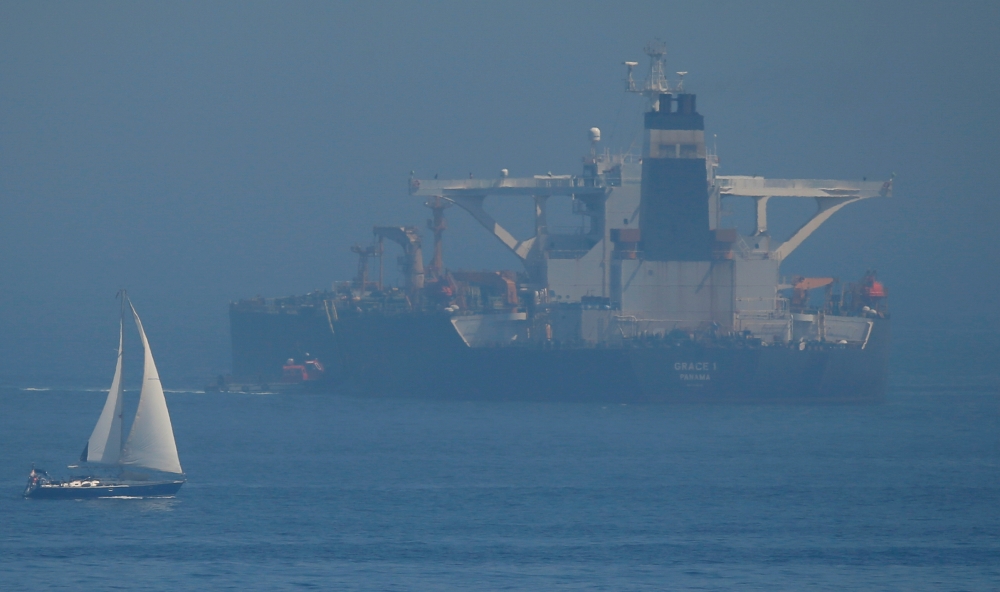 A sailboat sails as a boat approaches the boarding ladder of the Iranian oil tanker Grace 1 in the Strait of Gibraltar on Wednesday. -Reuters