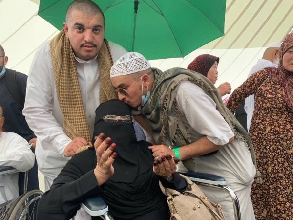 Umm Rakan, a Saudi mother in her 70s, is being kissed by on her sons as raises her hands in supplication. — Okaz
