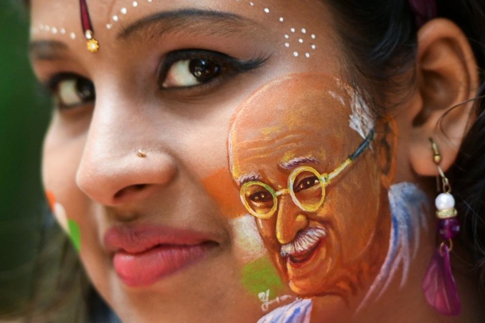 A girl poses for a picture with her face painted depicting a portrait of India's independence hero Mahatma Gandhi as the country celebrates its 73rd Independence Day, which marks the end of British colonial rule, in Bangalore on Thursday. — AFP
