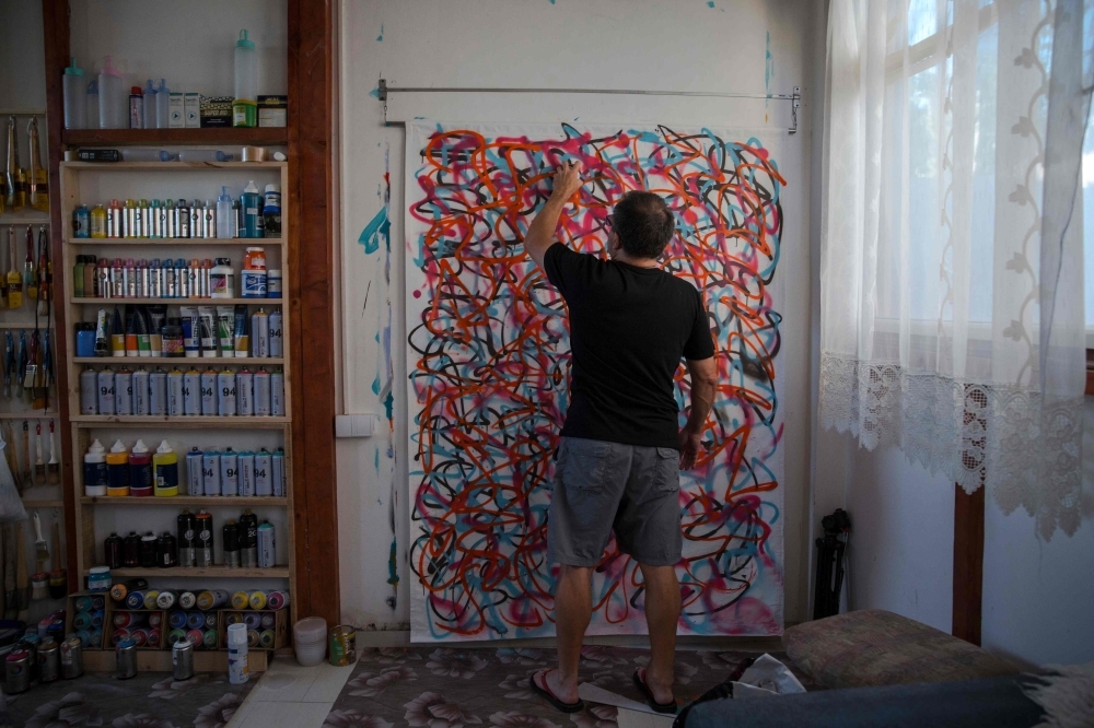 US artist Jeff Ross works on his drawing, in Pancevo, near Belgrade on Friday. -AFP 