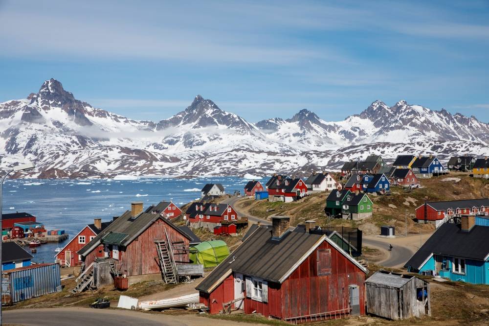 Snow covered mountains rise above the harbor and town of Tasiilaq, Greenland on June 15, 2018. -Reuters