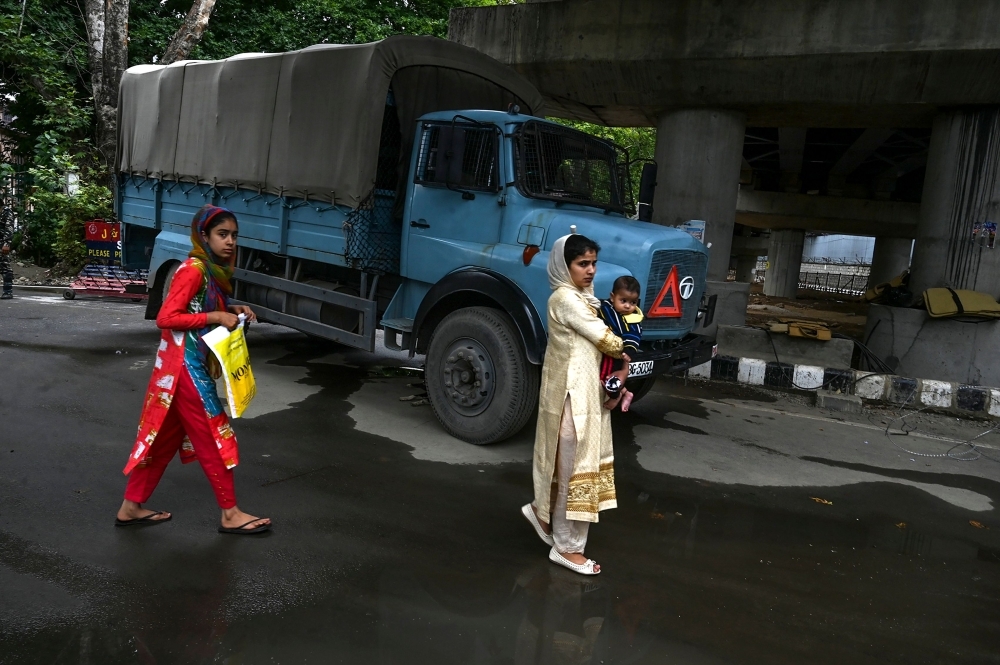 Kashmiri pedestrians walk past a security personnel vehicle in Srinagar on Saturday. Seventeen out of around 100 telephone exchanges were restored in the restive Kashmir Valley, the local police chief told AFP, after an almost two-week communications blackout. — AFP