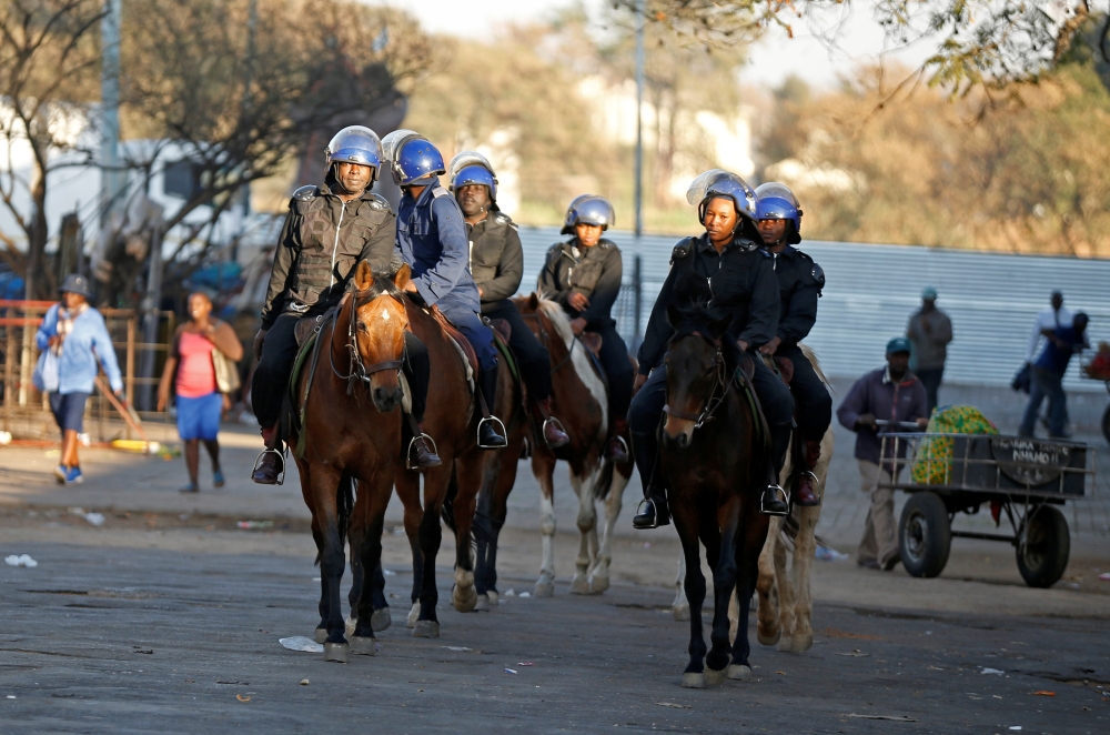 Riot police officers ride horses as they patrol the streets in Bulawayo, Zimbabwe, on Monday. -Reuters