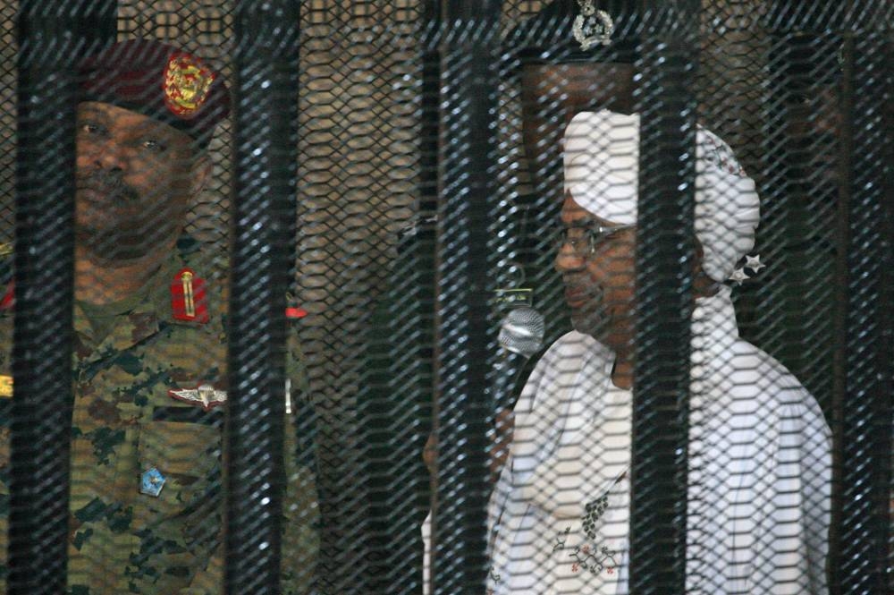 Sudan's deposed military ruler Omar Al-Bashir stands in a defendant's cage during the opening of his corruption trial in Khartoum, Monday. — AFP