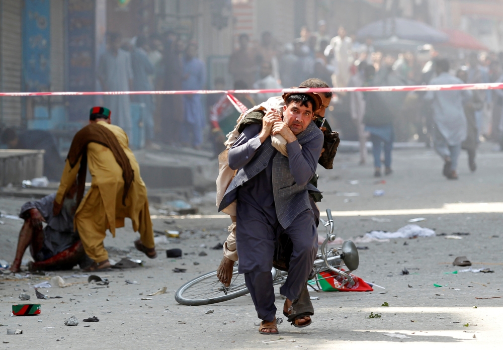 A man caries a wounded person to the hospital after a blast in Jalalabad, Afghanistan, on Monday. — Reuters