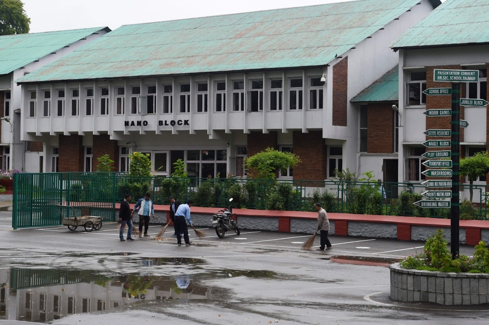 Workers clean the campus of an closed school in Srinagar, India, on Monday. — AFP