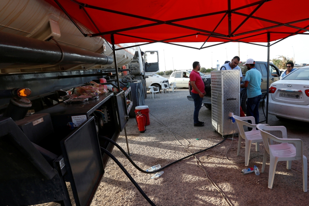 Men fill their cars with fuel from the state fuel distribution company, Brega, that is providing it from mobile trucks on the streets of Tripoli, Libya, in this Aug. 6, 2019 file photo. — Reuters