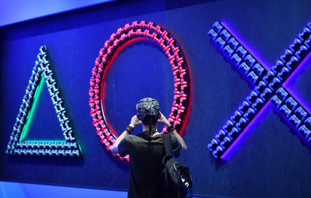 A man takes a picture of game consoles at the stand of Playstation during the media day of the Gamescom video games trade fair in Cologne, western Germany, on Tuesday. — AFP