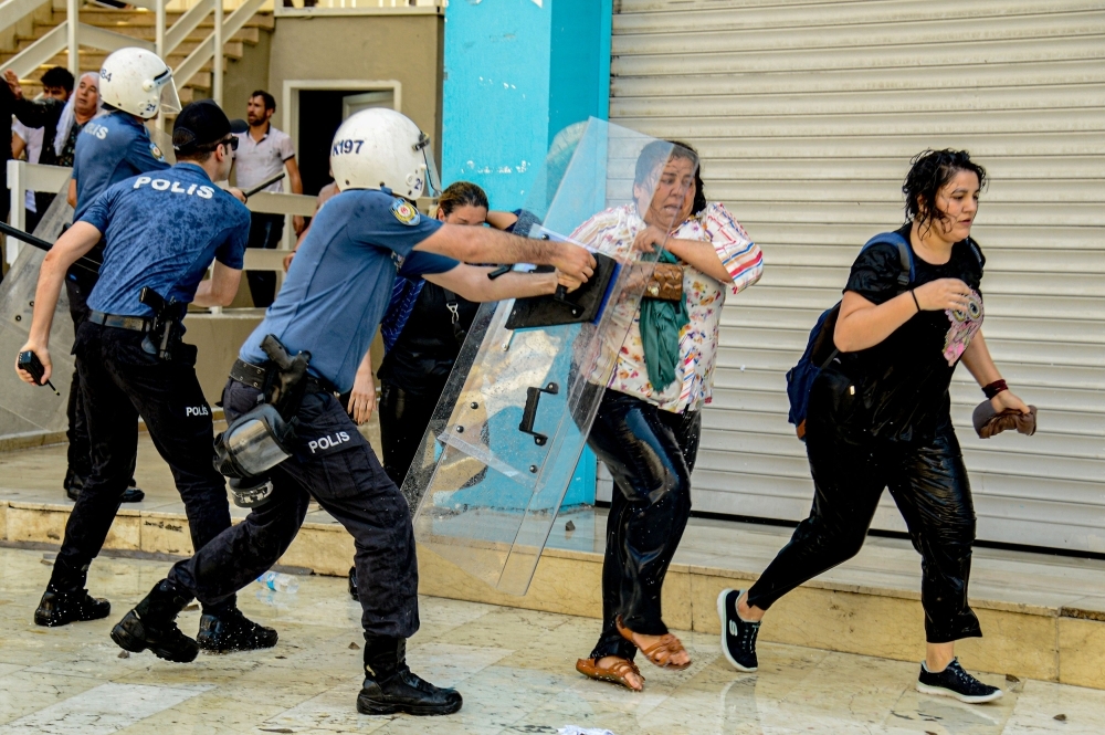 Turkish anti-riot police officers use their shields to disperse demonstrators during a protest against the replacement of Kurdish mayors with state officials in three cities, in Diyarbakir, Turkey, on Tuesday. — AFP