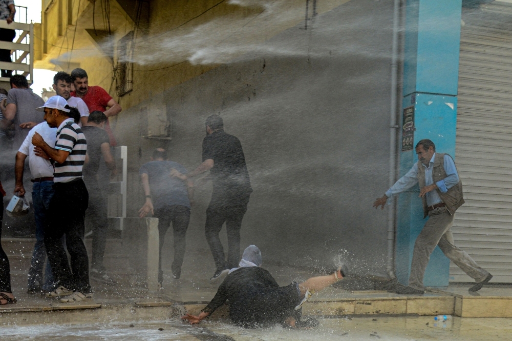 Turkish anti-riot police officers use their shields to disperse demonstrators during a protest against the replacement of Kurdish mayors with state officials in three cities, in Diyarbakir, Turkey, on Tuesday. — AFP