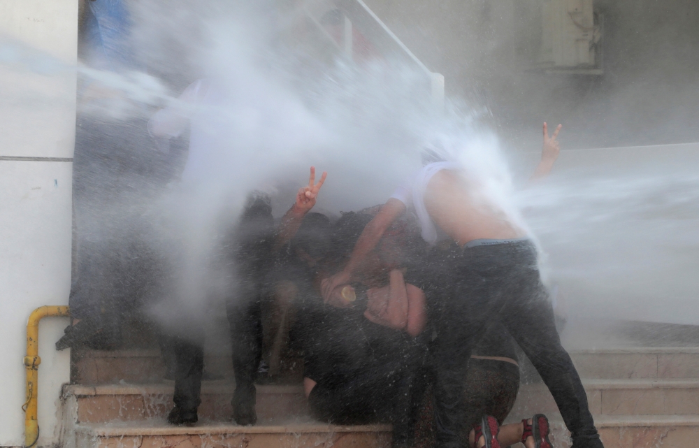 Turkish anti-riot police officers use their shields to disperse demonstrators during a protest against the replacement of Kurdish mayors with state officials in three cities, in Diyarbakir, Turkey, on Tuesday. — AFP