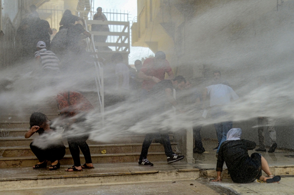 Turkish anti-riot police officers use their shields to disperse demonstrators during a protest against the replacement of Kurdish mayors with state officials in three cities, in Diyarbakir, Turkey, on Tuesday. — AFP