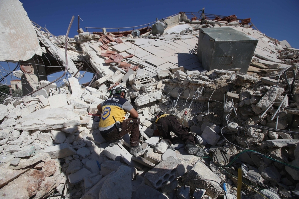 Members of the Syrian Civil Defense (White Helmets) look for the bodies amid the rubble following a reported government air strike in the village of Benin, about 30 km south of Idlib in northwestern Syria on Tuesday. — AFP