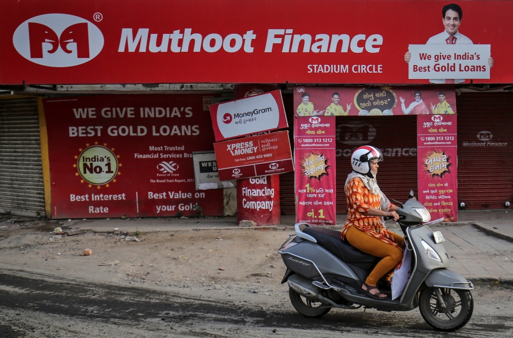 A woman rides her scooter past a Muthoot Finance branch in Ahmedabad, India, on Wednesday. — Reuters